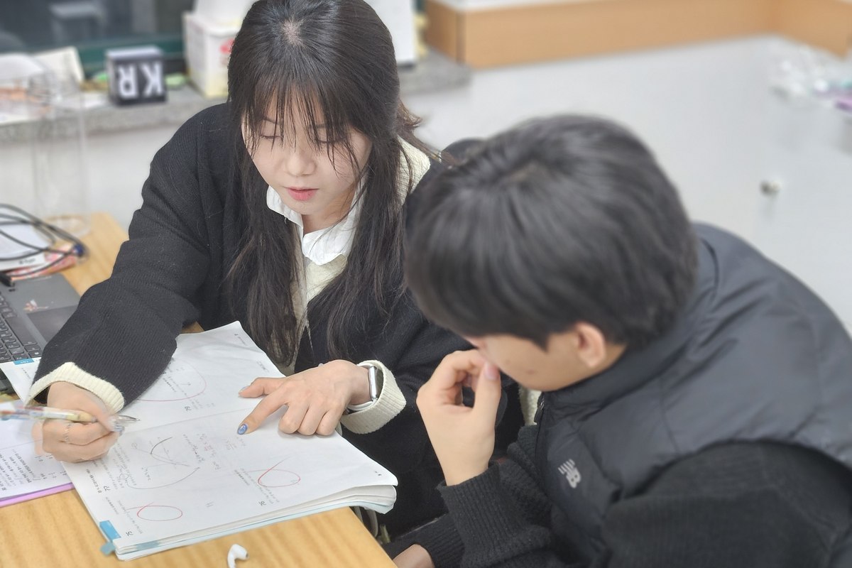 백마 고등수학학원 혜인쌤이 고등학생 옆에서 오답을 짚어가며 개인별 맞춤으로 지도하는 모습